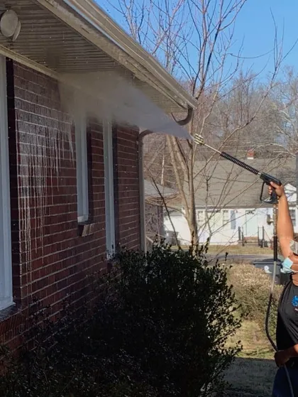 Technician washing the exterior of a brick home